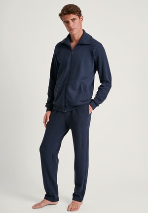 Marineblauer Fleece-Trainingsanzug mit Reißverschlussjacke und elastischen Bundhosen. Glatte Textur, lange Ärmel und seitliche Taschen in beiden Teilen.