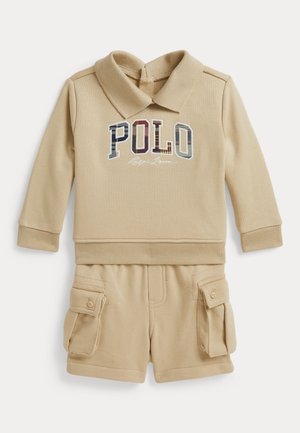 Beżowy strój dla malucha z długim rękawem i kołnierzykiem, bluza z napisem „POLO” oraz dopasowane krótkie spodnie typu cargo z kieszeniami na guziki.