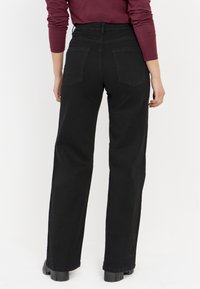 Zwarte hoge taille jeans met een rechte pijp, voorzien van twee achterzakken en minimale stiksels. Gemaakt van denim, hebben ze een gladde textuur.