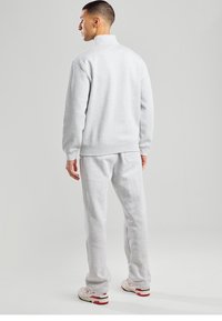 Gray cotton fleece tracksuit featuring a high collar, ribbed cuffs, and a relaxed fit. Pants include back pocket and elastic waistband.