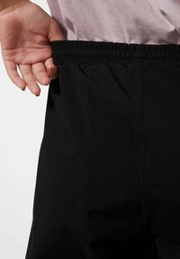 Pantalones negros con una cinturilla elástica. La textura parece suave y la tela tiene un acabado ligeramente brillante sin patrones visibles.