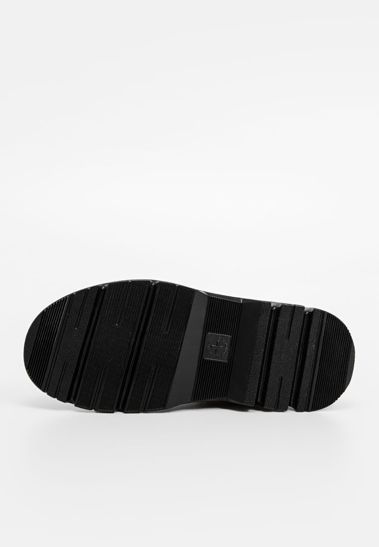 Semelle de chaussure en caoutchouc noir avec un motif texturé et rainuré. Présente un logo central et plusieurs rainures pour une meilleure adhérence.