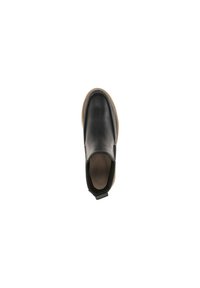 Zapato negro de cuero sin cordones con acabado texturizado, paneles elásticos en los laterales y suela de goma marrón. Diseño minimalista con una pestaña en la parte trasera.
