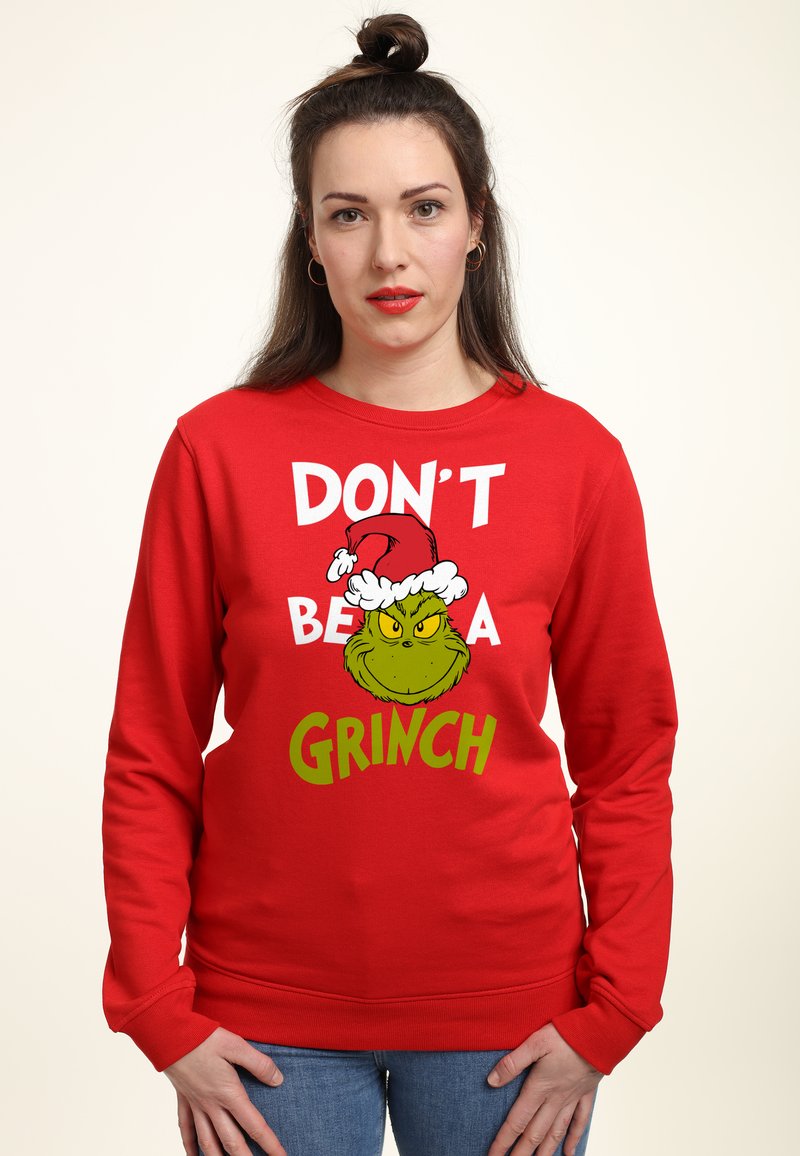 Červená mikina s potiskem Grinche v santovské čepici. Na textu je napsáno „NEBUĎ GRINCH“ bílou a zelenou barvou. Materiál: bavlna.