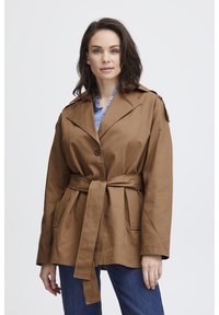 Braune, taillierte Jacke aus leichtem Material mit einem aufgeschlagenen Kragen, zwei Fronttaschen und Schulterklappen.