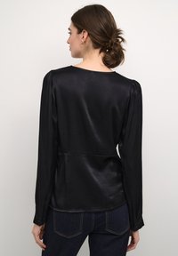 Blusa in satin nera con maniche lunghe, dettagli plissettati sulle spalle e una texture liscia. Presenta un collo rotondo e una vita aderente.