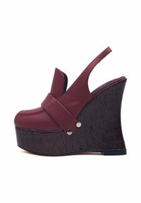 Scarpa con zeppa marrone bordeaux, con tomaia in pelle liscia, fascia ampia sul davanti e tacco texturizzato simile al legno. Presenta dettagli in metallo argentato.