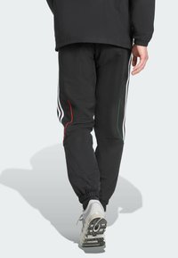 Schwarze Sporthosen mit weißen Seitenstreifen, roten und grünen Akzenten, elastischen Bündchen und einer glatten Stoffstruktur.