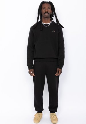 Sort sweatshirt og matchende joggers lavet af bomuldsblanding, med rund hals, ribbede manchetter og et lille broderet logo på brystet.