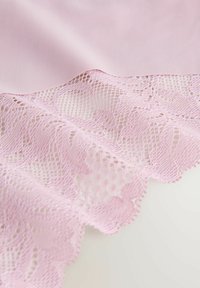 Taflă roz deschis cu dantelă zimțată, prezentând modele florale elaborate. Textura netedă a țesăturii contrastează cu designul delicat al dantelei.