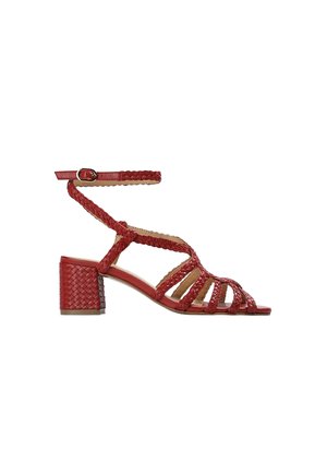 Sandalia roja de tacón bloque bajo con tiras trenzadas y cierre de hebilla en el tobillo, diseño con puntera abierta.