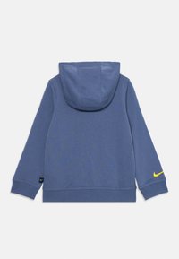 Felpa con cappuccio blu e maniche lunghe, realizzata in un tessuto morbido. Presenta un logo Nike giallo sulla manica destra e una tasca a marsupio.