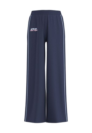 Pantalon de survêtement large bleu marine avec taille élastique, bandes blanches latérales et texte "Active Edit Motion Refined" sur la hanche gauche.