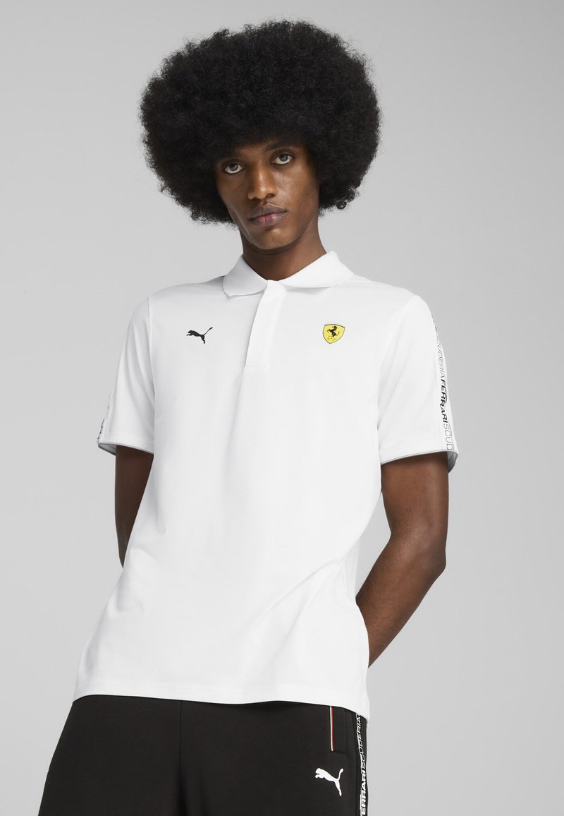 Hvid polo-shirt med krave, prydet med et gult Ferrari-logo og et sort Puma-logo. Korte ærmer med sorte accenter og mønstre.