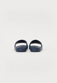 Navy blue slip-on sandals with wide straps, smooth rubber material, and a flat sole. Simple design with no visible brand detailing.