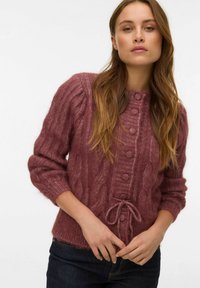 Mauve cable-knit sweater with a round neck and button closure, featuring a drawstring hem and ribbed cuffs. Made from soft, textured fabric.