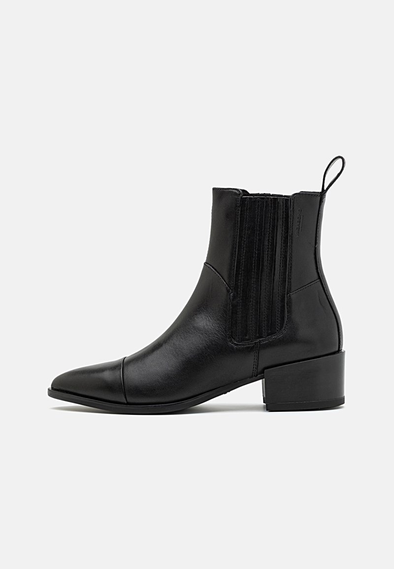 Bottine en cuir noir avec petit talon bloc, panneaux latéraux élastiques, bout pointu et languette à l'arrière.