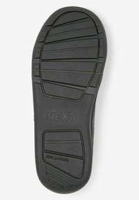 Semelle de chaussure en caoutchouc noir avec un design non marquant, dotée de rainures texturées et du nom de marque "NEXT" en relief.