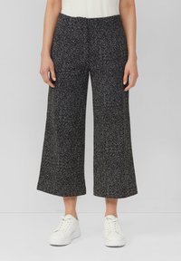 Pantalons large-jupe en pied de poule noir et blanc à taille haute, en tissu texturé, accompagnés de baskets blanches.