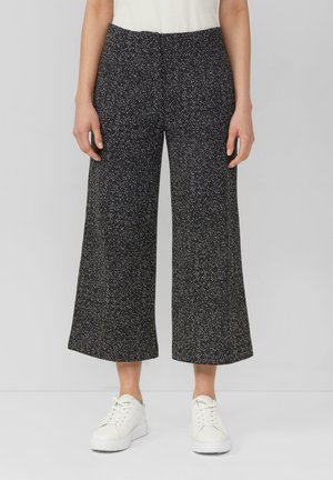 Pantalons large-jupe en pied de poule noir et blanc à taille haute, en tissu texturé, accompagnés de baskets blanches.