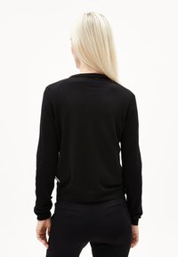 Svart långärmad tröja med rund halsringning, ribbade ärmslut och nederkant, visad från baksidan. Tyget ser mjukt ut med en slät yta.