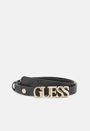 Ceinture en cuir noir avec boucle dorée portant l'inscription "GUESS" et un petit bouton doré sur un fond blanc uni.
