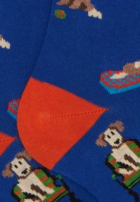 Calzini blu lavorati a maglia con un design di un cane giocoso, dettagli arancioni sul tallone e sulle punte, e un motivo lavorato a maglia testurizzato con colori vivaci.