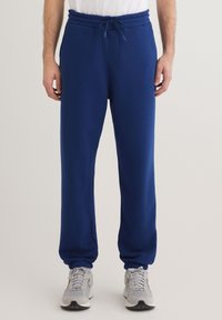 Navyblaue Sweatpants aus weichem Stoff mit einem Kordelzugbund, elastischen Bündchen und seitlichen Taschen, die einen lässigen Schnitt und Komfort bieten.