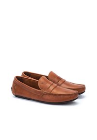 Mocasines de piel marrón con una superficie texturada y lisa. Presentan un acento cosido y un logo sutil. Diseño de fácil colocación con puntera redondeada.