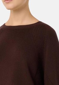 Maglione marrone lavorato a maglia con scollatura ampia e texture a coste sulle spalle. Tessuto morbido con vestibilità ampia e dettagli di design minimalisti.