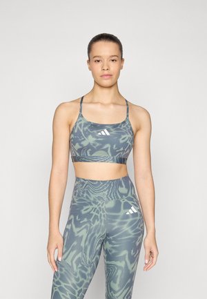 Set de sutien sport și colanți cu un model abstract verde. Materialul pare elastic. Dispune de bretele ajustabile și detalii cu logo pe ambele piese.
