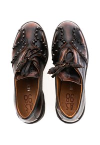 Brązowe skórzane buty z teksturowaną powierzchnią, akcentami w formie ćwieków oraz sznurowanym zapięciem na płaskiej podeszwie. Wnętrze wykończone brązową podszewką.