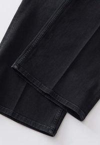 Jeans en denim noir avec une texture lisse, design à jambes droites et ourlets finis. Ils présentent une construction classique à cinq poches.