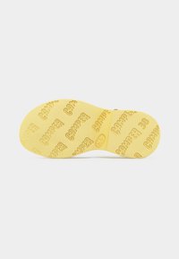 Κίτρινη σόλα παπουτσιού με επαναλαμβανόμενα μοτίβα κειμένου "CAMPER" και ανάγλυφο μέγεθος "38", εμφανίζεται σε απλό λευκό φόντο.