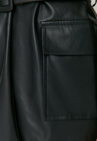 Zwarte leren shorts met een gladde textuur, voorzien van een grote zijzak en net gestikte naden, met een losse pasvorm en gestructureerd ontwerp.