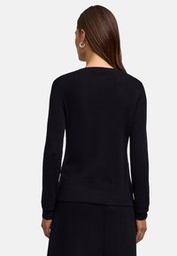 Schwarzer Langarm-Pullover aus strukturiertem Material, mit einem runden Halsausschnitt und gerippten Bündchen, in gerade geschnittener Silhouette.