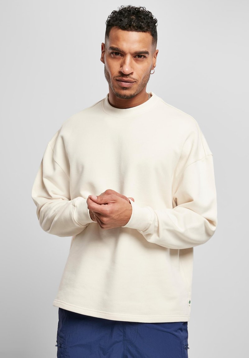Felpa color crema in cotone, con un fit rilassato, scollatura a girocollo e polsini a costine. Nota per il suo design minimalista.