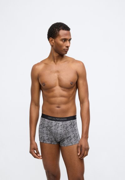 Γκρι μποξέρ σλιπ από μαλακό ύφασμα, με μαύρη λωρίδα με το λογότυπο και επαναλαμβανόμενο μοτίβο γεωμετρικών σχεδίων.