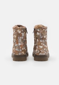 Botines marrones con estampado floral, forro de piel sintética y cierre de cremallera. Suela gruesa de goma con superficie texturizada.