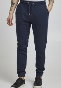 Marineblaue Jogginghosen in lockerer Passform, mit einem elastischen Bund und Kordelzug, Seitentaschen und gerippten Bündchen.