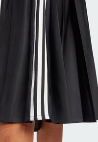 Black skirt with white vertical stripes on the sides, made of smooth fabric, features a flared design and mid-length cut.