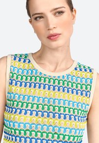 Top senza maniche lavorato a maglia con un motivo multicolore di verde, blu e giallo, con un colletto chiaro e un design aperto e testurizzato.