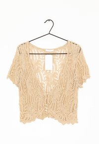 Cárdigan beige de ganchillo con mangas cortas, apertura frontal y detalles intrincados con patrón de hojas. Etiqueta colgante adjunta en el centro de la parte trasera.