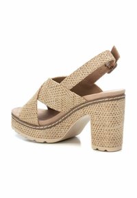 Sandalias de plataforma trenzadas en beige con un alto tacón cuadrado, correas entrecruzadas y una correa ajustable en la parte trasera. Plantilla de textura suave.