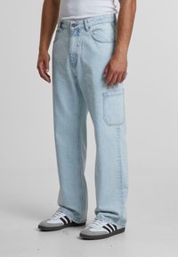 Pantaloni cargo din denim de culoare bleumarin deschis, cu o croială lejeră, având un buzunar lateral, cusături în contrast și un design clasic cu cinci buzunare.
