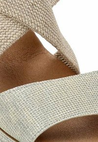 Sandalias de yute beige con un diseño de tiras cruzadas y un upper texturizado, con una plantilla marrón lisa y una amplia correa para el tobillo.