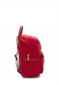 Zaino rosso con tasca frontale e zip dorata, vista laterale che mostra il retro imbottito e le spalline regolabili.