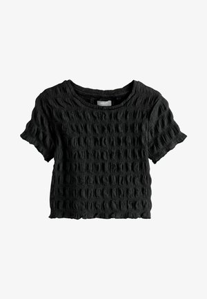 Melna teksturēta īsām piedurknēm blūze ar apaļu kakla izgriezumu, kurai ir grumbuļaina raksts un īsa piegriezums. Pabeigta ar neapstrādātu apdari.