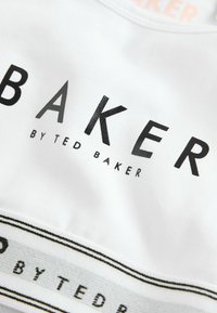 Hvid bomulds t-shirt med fed sort "BAKER" tekst, med en logo-stribe nedenfor i sort og hvid. Glat tekstur, klassisk crew neck design.
