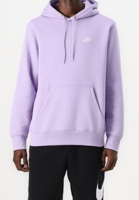 Vaalean violetti huppari, jossa on etutasku ja kiristysnauhallinen huppu. Rintakehässä pieni valkoinen Nike-logo. Pehmeä, sileä pinta.